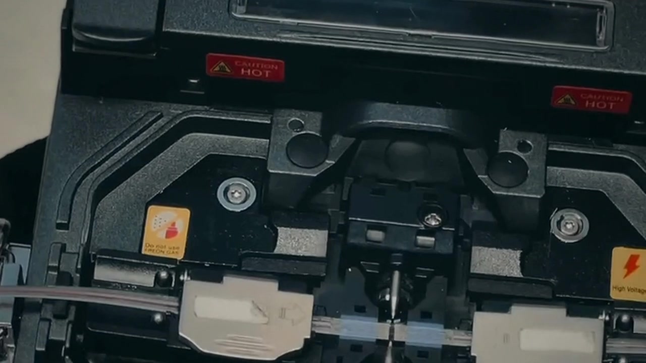 Close-ups of ribbon fiber preparation and a fusion splicer in use.
